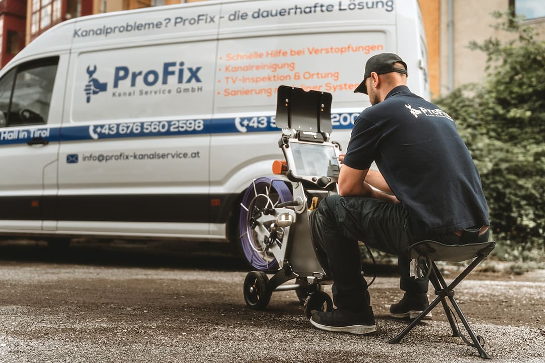 Firmenwagen von ProFix mit aufgedruckten Leistungen, davor ein Techniker am Kamerawagen